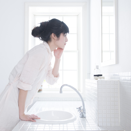 woman looking at face in mirror - gluthathione supplment - anti ageing product - beauty news - beauty bag - handbag.com