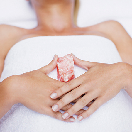 woman lying in bed with a crystal - how to relax with crystal therapy like victoria beckham - gym bag - handbag
